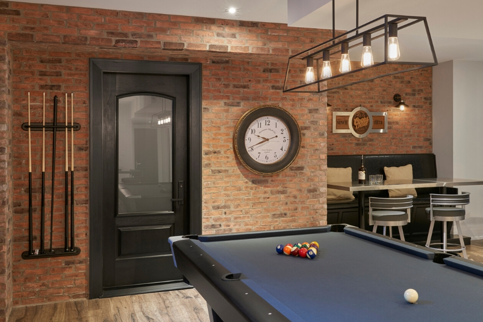 Rustic basement with brick walls, wood-look floors and pool table |Desgin by Cynthia Soda